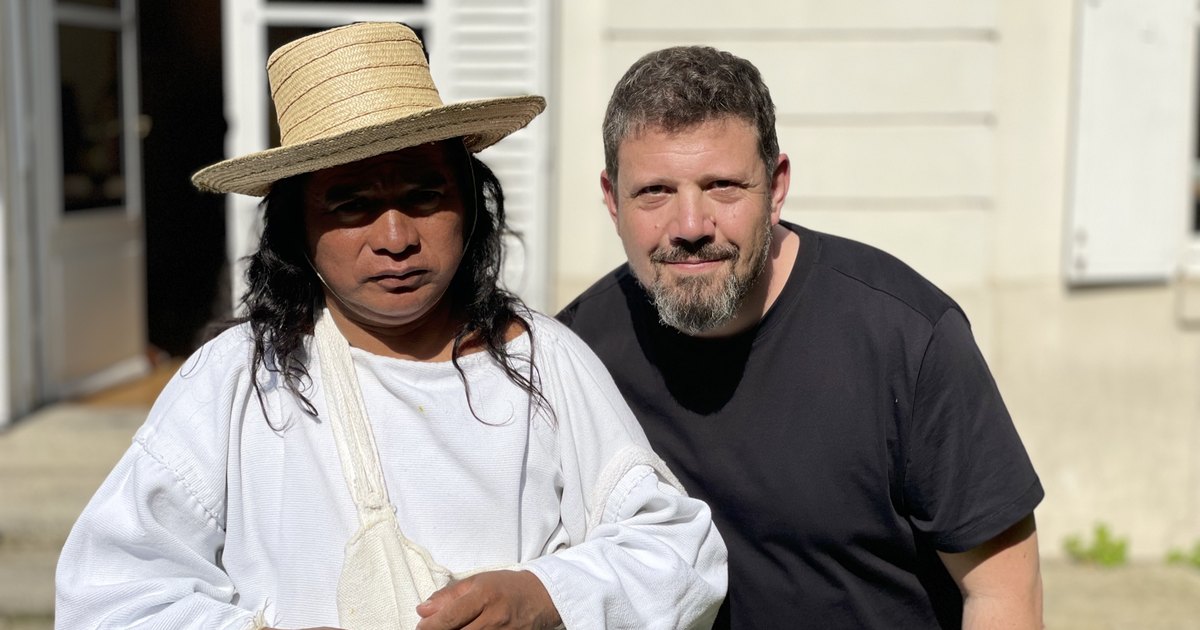 Mihai standing beside a Kogi man dressed in white, with a woven straw hat and shoulder bag