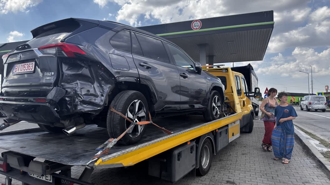 The car being towed away, with two of my children standing on the pavement, unharmed