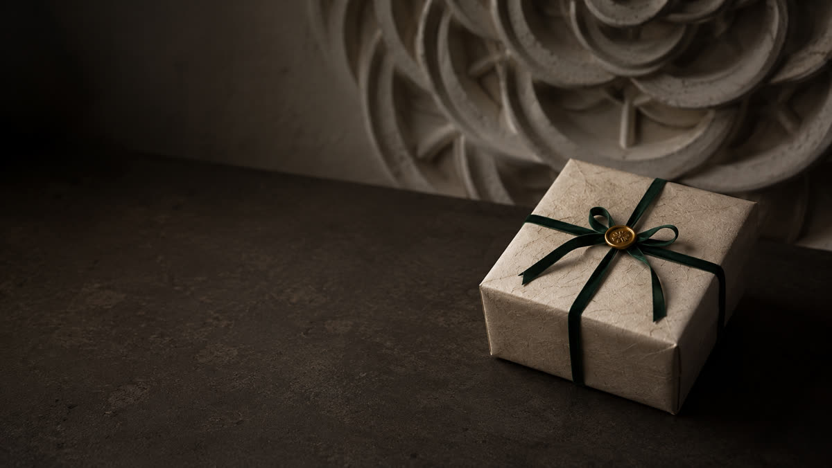 A wrapped gift with an emerald ribbon and a gold wax seal