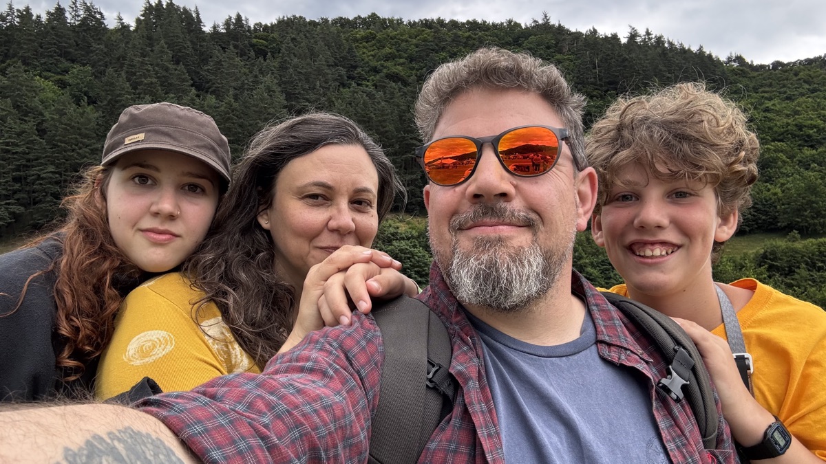 Mihai with his family, forest hills behind them