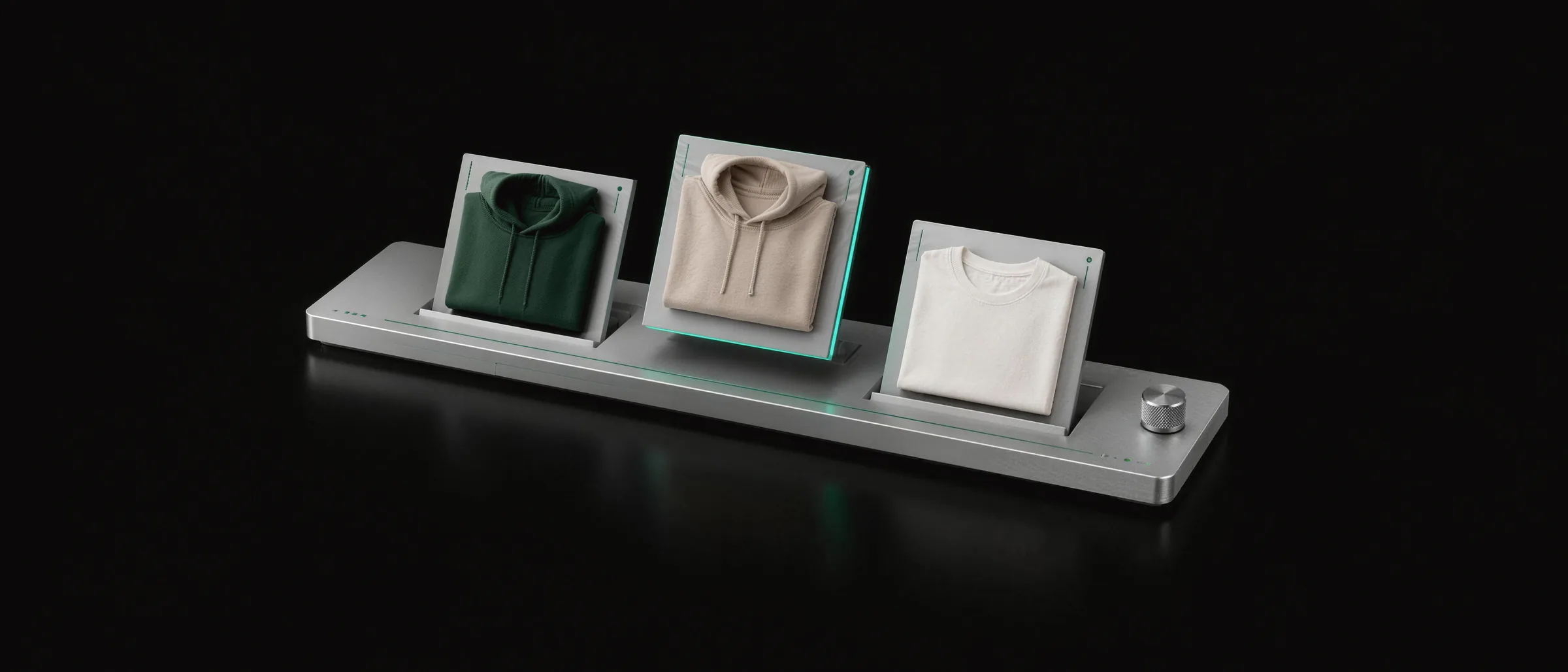 An aluminium display tray holding three product cards, a forest green hoodie, a sand hoodie and a cream tee, with the middle card lifted on an emerald edge as it is rearranged.